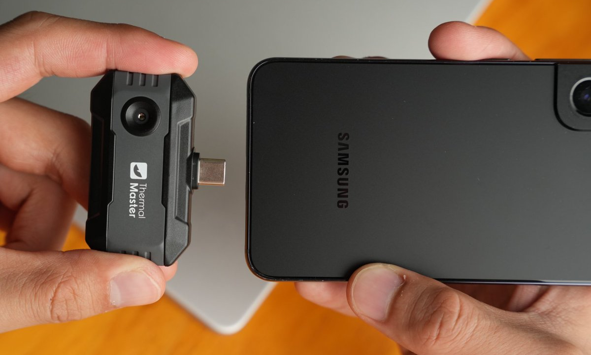Preparing to insert the small thermal imager into the phone
