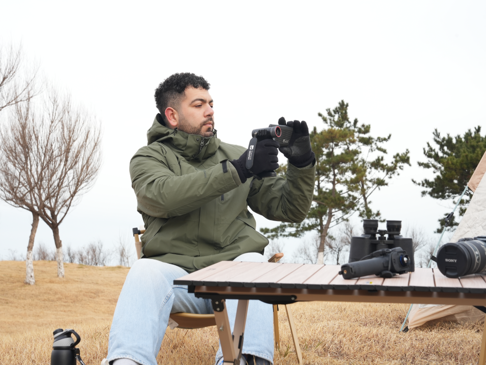Man using a Thermal Master handheld thermal camera for outdoor wildlife observation.