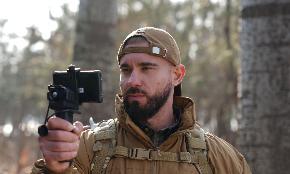 A man uses birdwatching binoculars to inspect the forest.