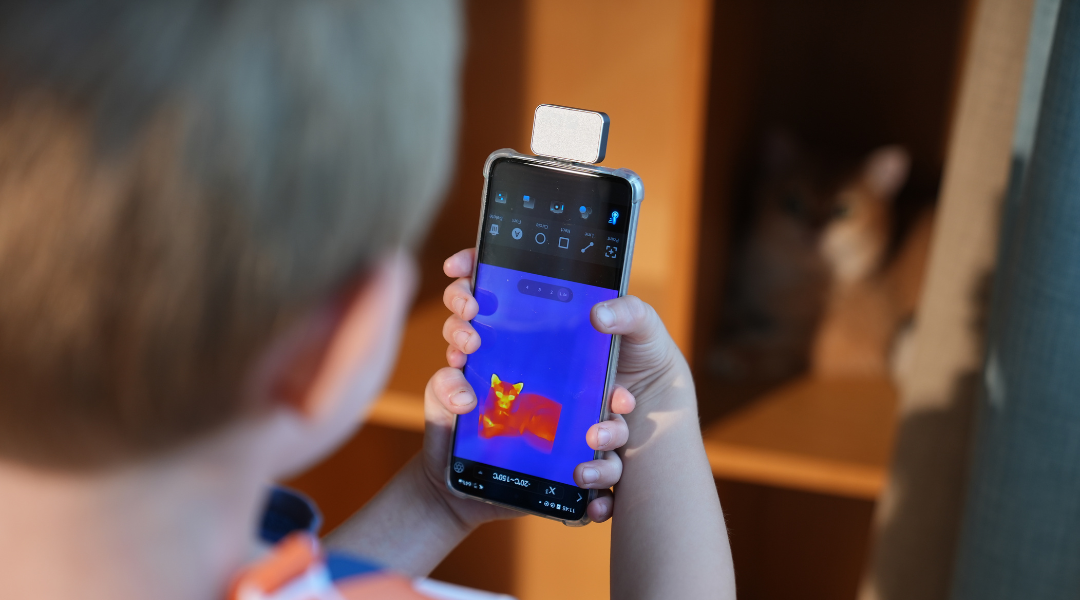 A child holding a mobile phone thermal imager.