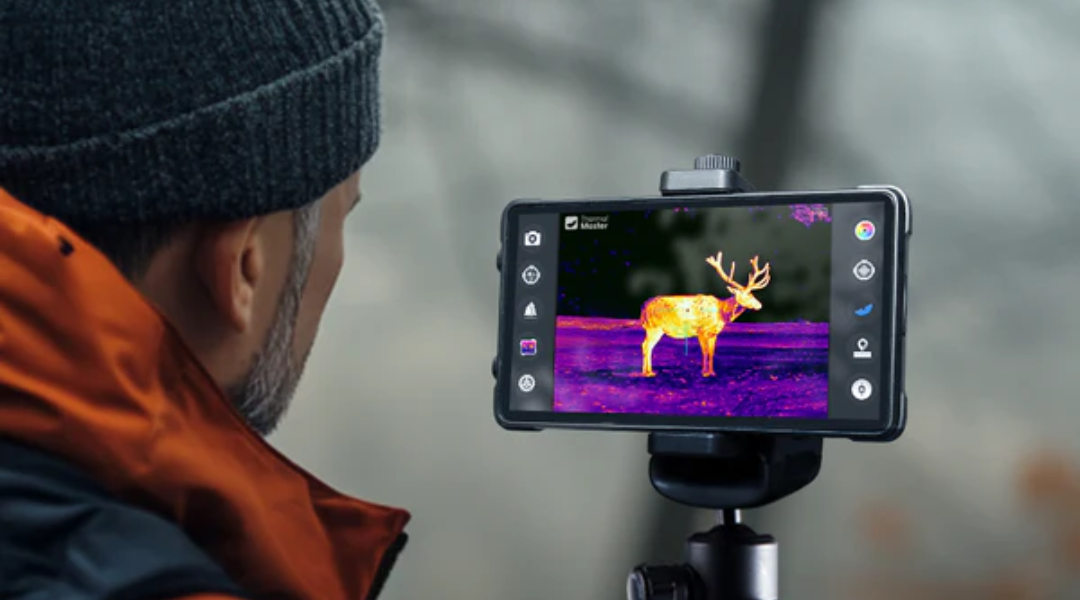 A man observes elk using a thermal monocular.