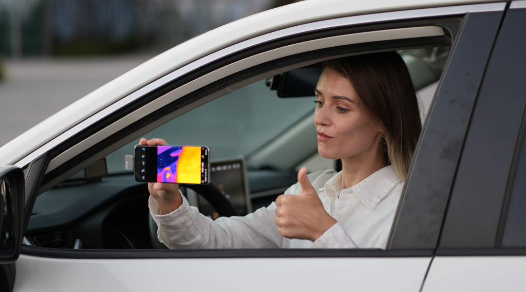 A woman uses a mobile phone thermal imager inside a car.