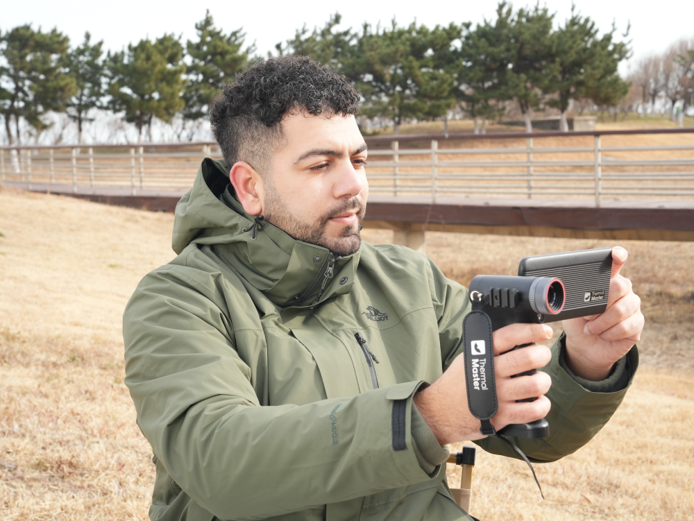 Man using a Thermal Master thermal monocular outdoors for wildlife observation.