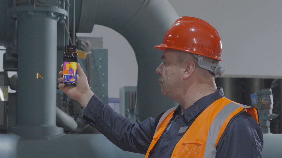Technician using a Thermal Master smartphone thermal camera to inspect industrial equipment.