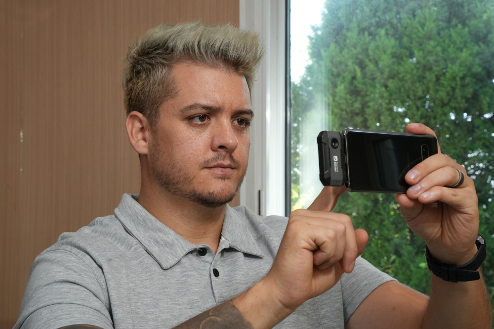 Man using a Thermal Master P1 with a smartphone for indoor thermal inspection.