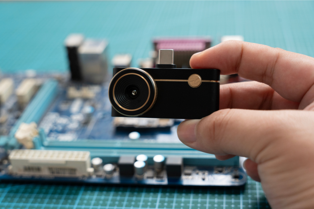 Thermal Master P3 smartphone thermal camera held over a circuit board for PCB inspection.